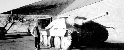 Bill Kofoed standing beside a German tank, painted white for winter battle, at the Bastogne Historical Center.