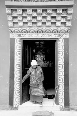 At the Tibetan settlement of Hyangia, a woman emerges from a temple which contains a giant prayer wheel.