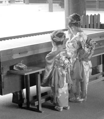 Children dressed in traditional attire worshiping at a Tokyo shrine. 