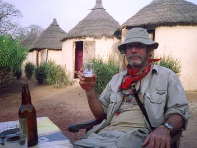 A cold beer made sleeping in the individual huts, seen here behind Jim, a little more acceptable in Banfora’s Campement Kegnigohi village.