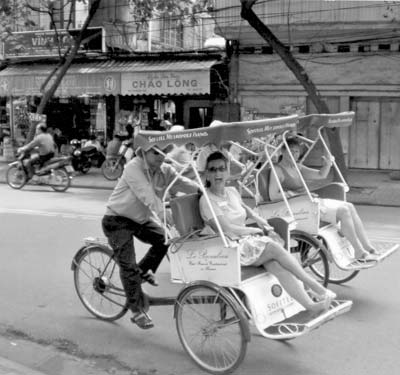 Suzy Davis (foreground) riding a rickshaw in Hanoi.