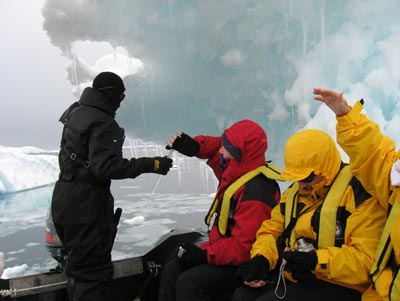 Zodiac driver with passengers under icicle-laden berg near Devil Island.