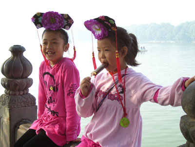 Children posing for photos at the Summer Palace, with Kunming Lake in the background.