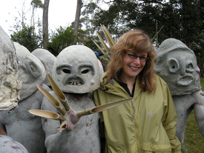 Josie Scott with the fierce Pogla Mudmen at the Tumbuna Sing Sing in Mt. Hagen. They originally devised their mud-head masks and attached long, sharp pieces of  bamboo  to their fingers as a way to scare their enemies into thinking they were the angry ghosts of the rival clan’s dead.