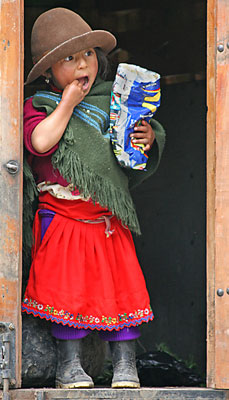 Girl standing in the back of a truck munching on snacks, glimpsed on the drive to Ingapirca.