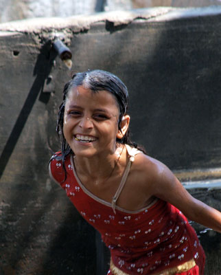 A young girl plays in an open-air laundry stall while her father works nearby.