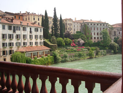 Pastel-colored houses on the banks of the Brenta River as seen from the Ponte Vecchio in Bassano del Grappa.