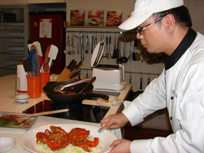 Chef Alfie wipes drips off the plate of Singapore Chili Crab.