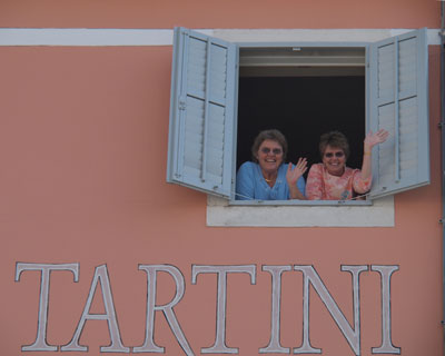 Sisters wave from their hotel room overlooking Piran’s town square. Photo by Luka Esenko.