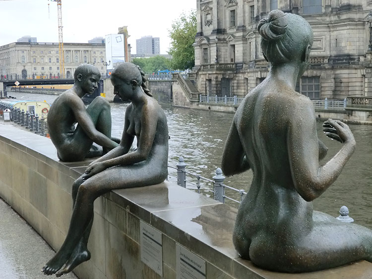 Bronze statues lining the Spree River.