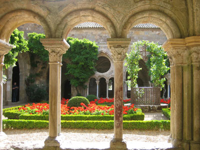 The cloister garden at the Abbey of Fontfroide, dating from 1093, is planted with bright red geraniums.