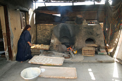 A woman baking bread, which is eaten with every meal.