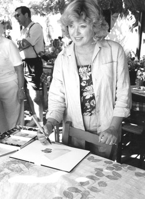 Artist Pamela Rogers, in one of the island’s tavernas, applies color to a street-scene painting. 