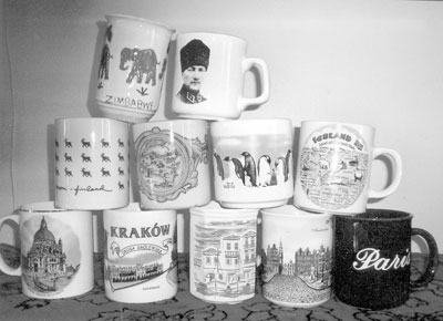 Top row: Mugs from Zimbabwe (this one was handmade in a craft school) and Turkey (picturing Ataturk). Middle: Scattered reindeer from Finland, a map of Sicily, penguins from Antarctica and a map of Iceland. Bottom: the lagoons of Venice; Kraków, Poland; rooftops of Athens; a street scene in Amsterdam, and Paris. 
