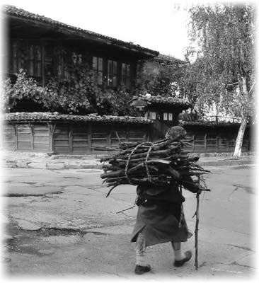 A woman in Jeravna carries her load past preserved houses.