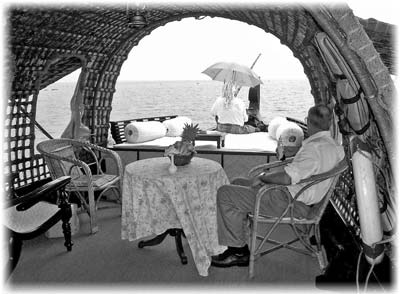 Chuck sits in our kettuvallam, a boat designed to carry rice but now converted to a houseboat, as we cruise the Kerala backwaters and canals.