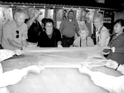 Group members help in stretching silk at a silk factory.