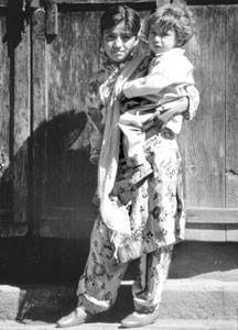 A young girl holding her younger sister in Bahrain, Pakistan.