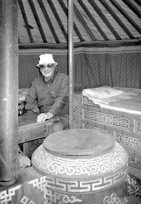 Wayne at the table/desk in their ger with decorated bed and potbellied stove. Photos: Schild