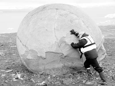 Swedish naturalist Magnus Forsberg tests his strength on an enormous round boulder typical of those found on Champ Island, Franz Joseph Land.