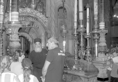 A bossy Greek orthodox priest controls entry to the burial cave (the 14th Station of the Cross) at the basilica of Jerusalem’s Church of the Holy Sepulchre. — Photo by Roger Canfield.