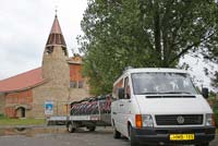 Our mini-van and trailer  “pose” before a village church.