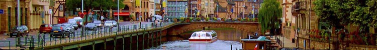 A canal boat, such as this one passing under the bridge, is a good way to tour Strasbourg, where the River Ill winds through the city. (The boat at right is one of the city’s many floating restaurants.)