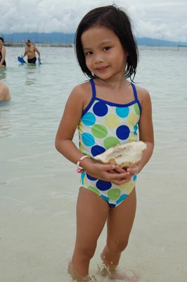 A child holds her prize from the sea — Pandan Island, Palawan.