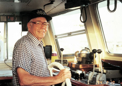 Luther Blount (1916-2006), founder of ACCL, stands at the helm of one of the 300 ships he built.