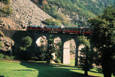 Approaching the Bernina Railroad’s 9-arched spiral viaduct at Brusio, Switzerland, photographers elbow for window space.