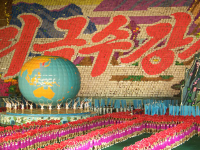 The Arirang Mass Games features performers in brightly colored costumes on the floor plus a changing, detailed background created by colored flip cards in the stands.