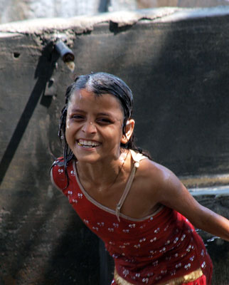 A young girl plays in an open-air laundry stall while her father works nearby.