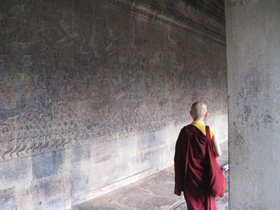 A young monk studies an intricately carved wall at Angkor Wat.