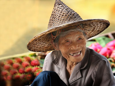 An old woman smiles at us in the floating market town of Damnoen Saduak, Thailand.