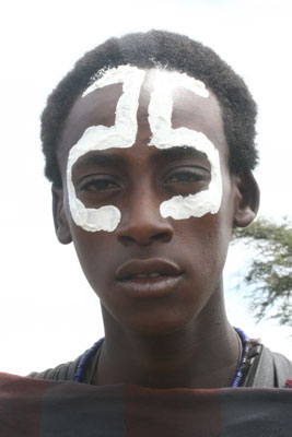 A Maasai boy with his face painted for the ceremony to signify his transition into manhood.