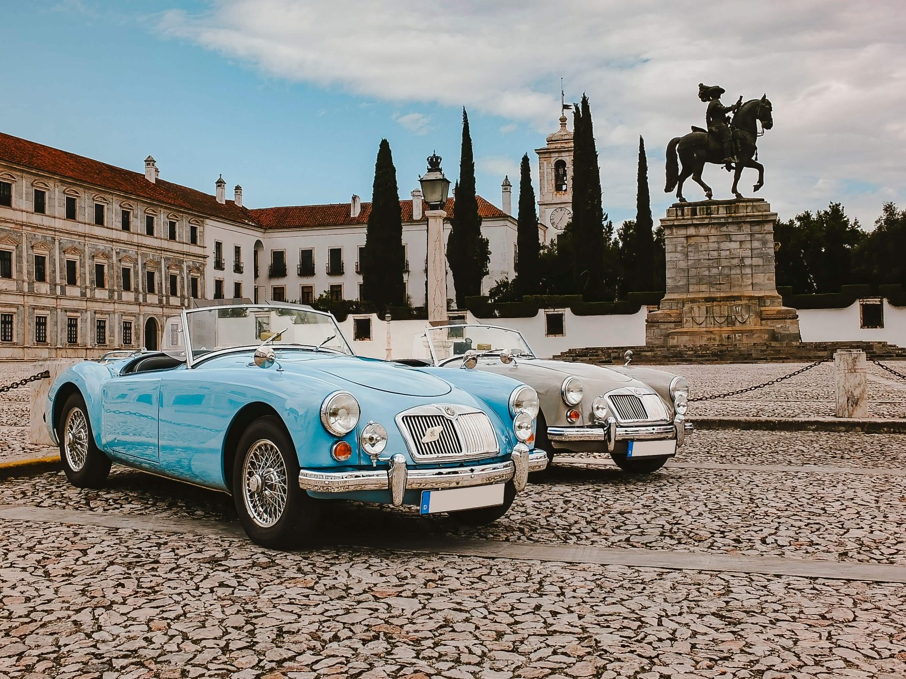 Two vintage MGA Roadsters in front of a castle in Portugal