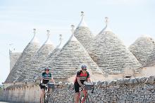 Bicyclists riding past trulli (limestone huts) in Alberobello, Puglia, Italy. Photo courtesy of Butterfield & Robinson