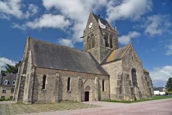 During the D-Day invasion, off-course American paratroopers landed in the middle of the village of Ste-Mère Eglise. One paratrooper’s chute caught on a church spire, which the village commemorates today with a mannequin dangling on the church. Photo by Cameron Hewitt