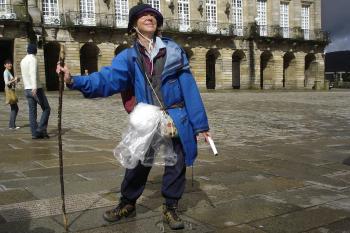 A jubilant pilgrim on Spain’s Camino de Santiago marks the end of her journey in front of the cathedral in Santiago de Compostela. Photo by Rick Steves