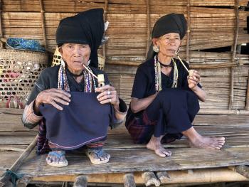 Two Akhi women smoking bamboo pipes.