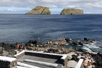 Concrete walkways all around Terceira Island lead to the ocean. In the background are the Goat Islands, now uninhabited by man or goat — Azores. Photo by Norman Dailey