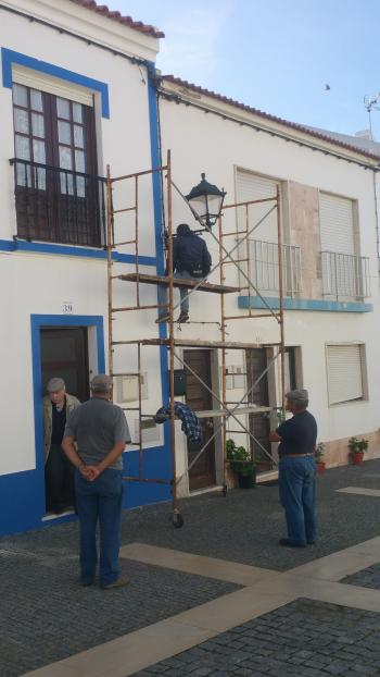 Painters whitewashing a building in traditional style in Porto Côvo.