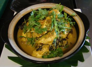 A bowl of the Rakhine Hot and Spicy Chicken Curry with garnish.