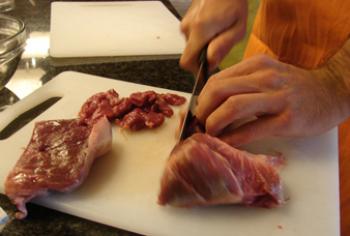 Cutting the beef into bite-sized pieces.