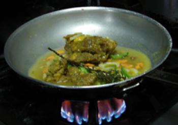 Marinated goat meat added to the frying pan.