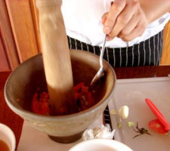 Using a mortar and pestle to mash the beans, chilies, garlic, shrimp paste and sugar. Photo by Sandra Scott