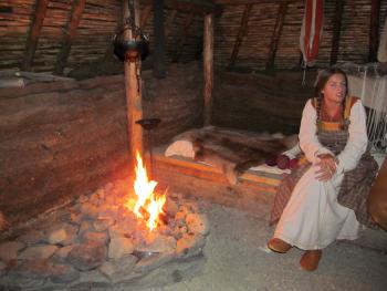 An interpreter dressed in Norse garb inside the main communal hall (A), part of Viking complex A-B-C in L’Anse aux Meadows — Newfoundland, Canada.