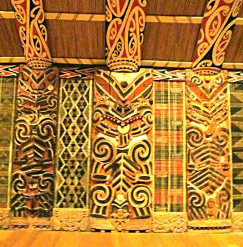 These are <i>poupou</i>, or carved wall figures representing ancestors, with <i>tukutuku</i>, ornamental woven-reed latticework, in between. All are inside a <i>wharenui</i> (meeting house) displayed in the Auckland Museum.
