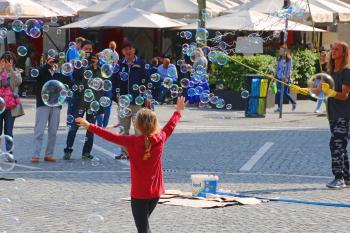 A young girl chasing bubbles in the center of Ljubljana.