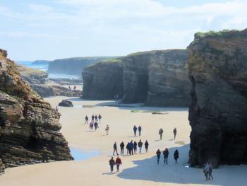 Travelers exploring the Beach of the Cathedrals at low tide.